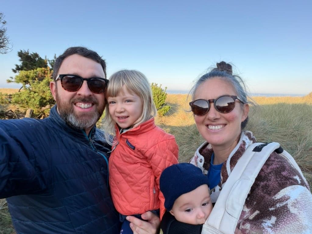 Leon with his wife and their two children outdoors by the coast